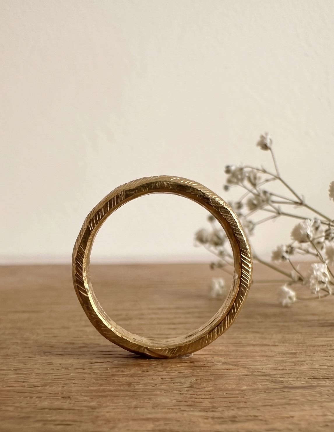 Anillo rústico de bronce de pie, mostrando su banda cerrada y textura facetada artesanal