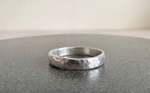 Anillo de plata martillado Ley 950 hecho a mano, vista lateral sobre superficie gris